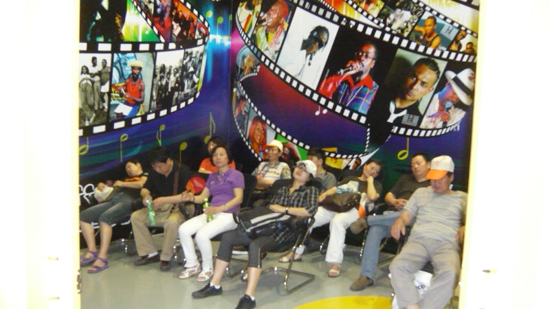 P1030192.JPG - This was in the Jamaica Pavilion, where they had a room, with chairs and air conditioning, where you could watch reggae videos.  As you can see, the room was popular, though not so much because of the reggae.